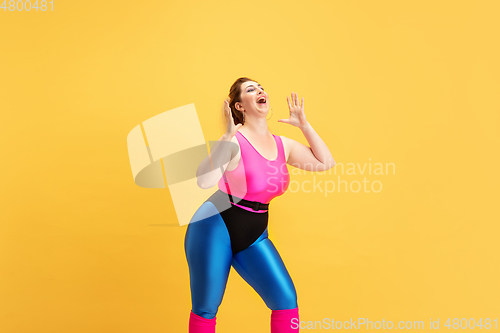 Image of Young caucasian plus size female model\'s training on yellow background