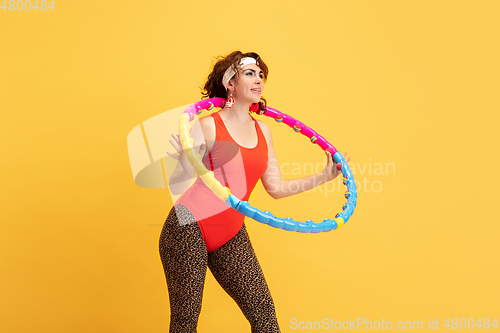 Image of Young caucasian plus size female model\'s training on yellow background