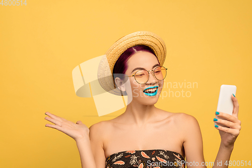 Image of Portrait of beautiful young woman with bright make-up isolated on yellow studio background