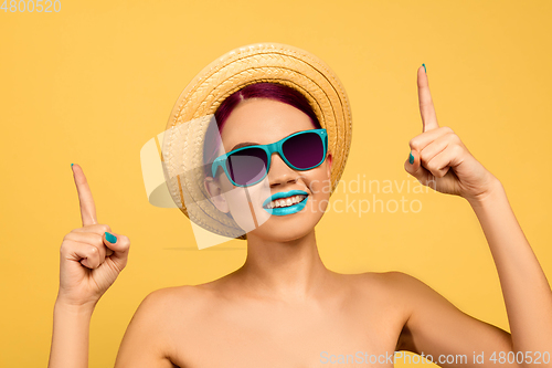 Image of Portrait of beautiful young woman with bright make-up isolated on yellow studio background