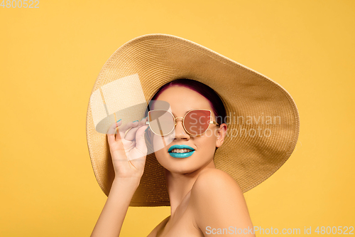 Image of Portrait of beautiful young woman with bright make-up isolated on yellow studio background