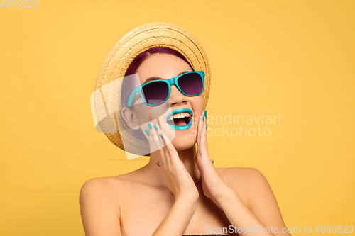 Image of Portrait of beautiful young woman with bright make-up isolated on yellow studio background