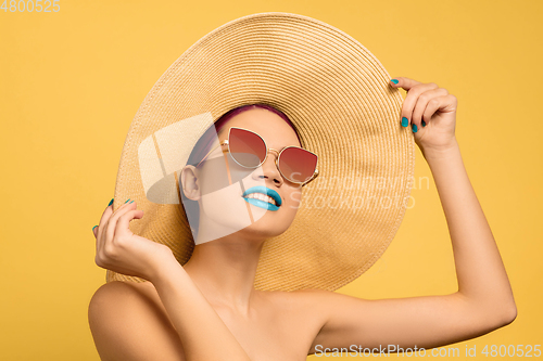 Image of Portrait of beautiful young woman with bright make-up isolated on yellow studio background