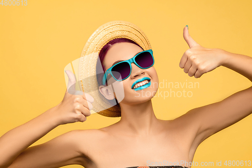 Image of Portrait of beautiful young woman with bright make-up isolated on yellow studio background