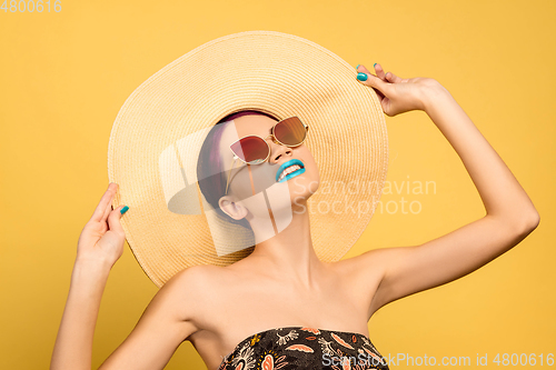 Image of Portrait of beautiful young woman with bright make-up isolated on yellow studio background