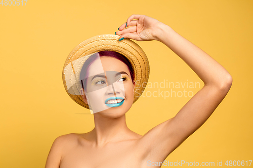 Image of Portrait of beautiful young woman with bright make-up isolated on yellow studio background