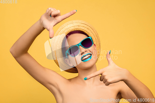 Image of Portrait of beautiful young woman with bright make-up isolated on yellow studio background