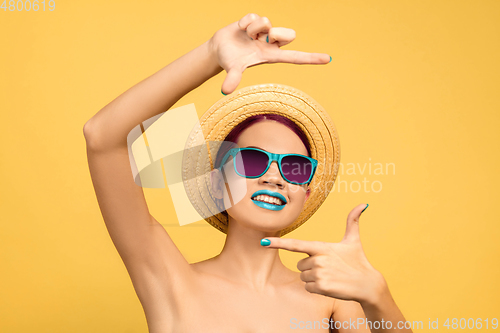 Image of Portrait of beautiful young woman with bright make-up isolated on yellow studio background