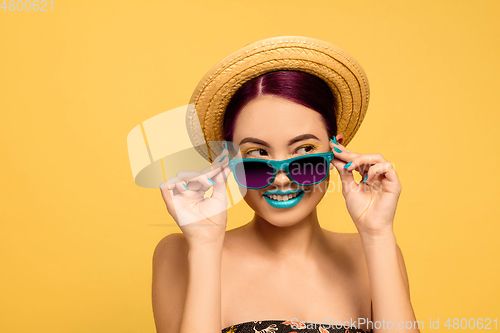 Image of Portrait of beautiful young woman with bright make-up isolated on yellow studio background