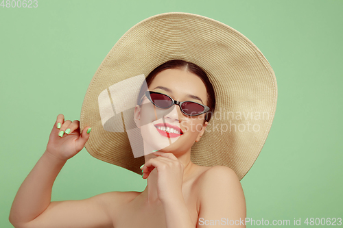 Image of Portrait of beautiful young woman with bright make-up isolated on green studio background