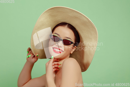 Image of Portrait of beautiful young woman with bright make-up isolated on green studio background