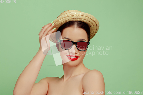 Image of Portrait of beautiful young woman with bright make-up isolated on green studio background