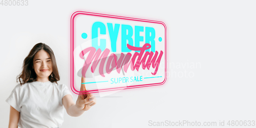 Image of Half-length close up portrait of young woman in neon light with cyber monday lettering