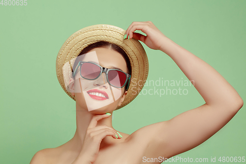 Image of Portrait of beautiful young woman with bright make-up isolated on green studio background