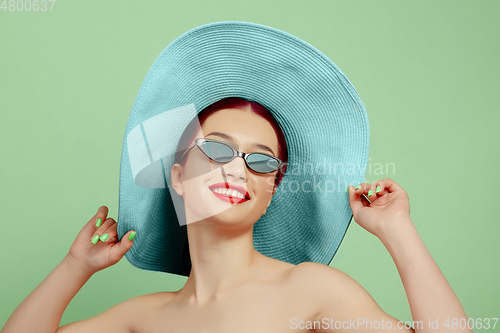 Image of Portrait of beautiful young woman with bright make-up isolated on green studio background