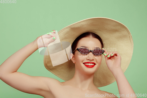 Image of Portrait of beautiful young woman with bright make-up isolated on green studio background