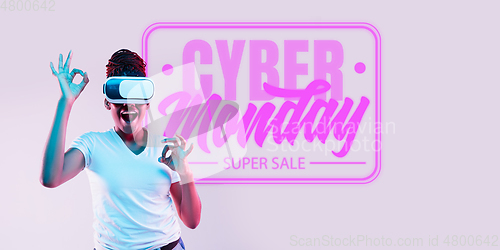 Image of Half-length close up portrait of young woman in neon light with cyber monday lettering