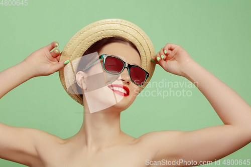 Image of Portrait of beautiful young woman with bright make-up isolated on green studio background