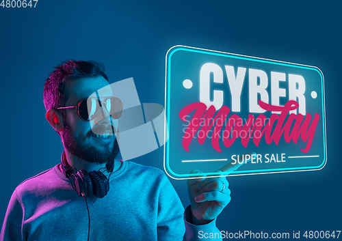 Image of Half-length close up portrait of young man in neon light with cyber monday lettering