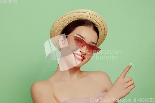 Image of Portrait of beautiful young woman with bright make-up isolated on green studio background