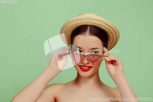Image of Portrait of beautiful young woman with bright make-up isolated on green studio background