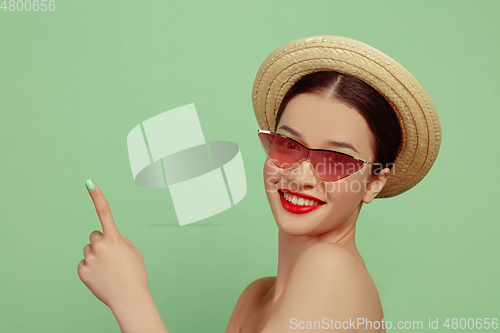 Image of Portrait of beautiful young woman with bright make-up isolated on green studio background