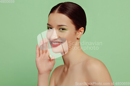 Image of Portrait of beautiful young woman with bright make-up isolated on green studio background