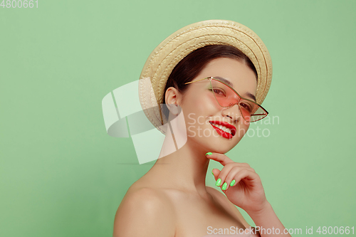 Image of Portrait of beautiful young woman with bright make-up isolated on green studio background