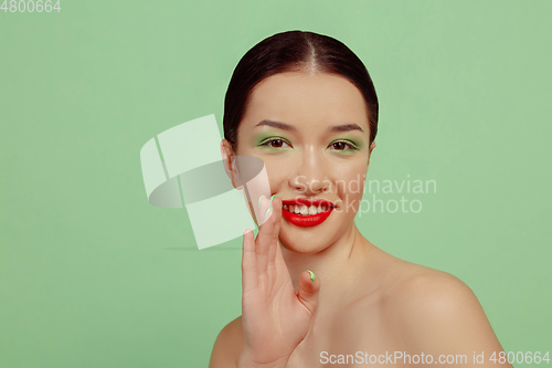 Image of Portrait of beautiful young woman with bright make-up isolated on green studio background