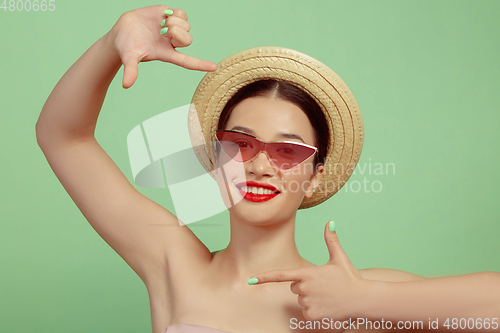 Image of Portrait of beautiful young woman with bright make-up isolated on green studio background