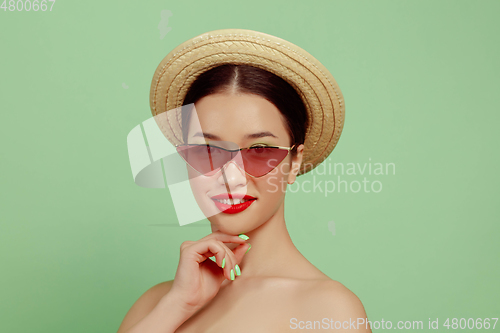 Image of Portrait of beautiful young woman with bright make-up isolated on green studio background