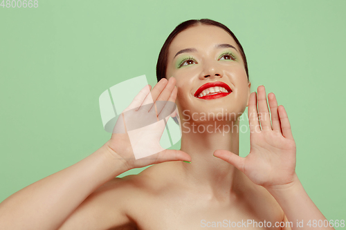 Image of Portrait of beautiful young woman with bright make-up isolated on green studio background