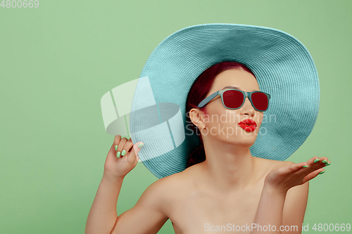 Image of Portrait of beautiful young woman with bright make-up isolated on green studio background