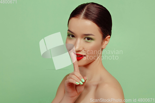 Image of Portrait of beautiful young woman with bright make-up isolated on green studio background