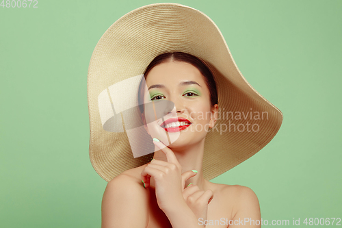 Image of Portrait of beautiful young woman with bright make-up isolated on green studio background