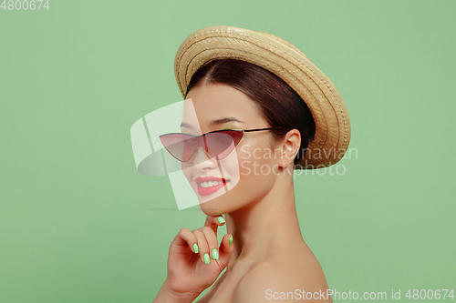 Image of Portrait of beautiful young woman with bright make-up isolated on green studio background