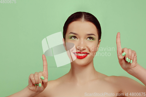 Image of Portrait of beautiful young woman with bright make-up isolated on green studio background