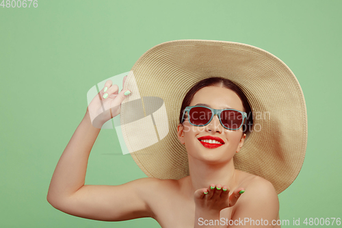 Image of Portrait of beautiful young woman with bright make-up isolated on green studio background