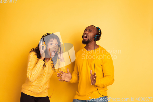 Image of Young emotional african-american man and woman on yellow background