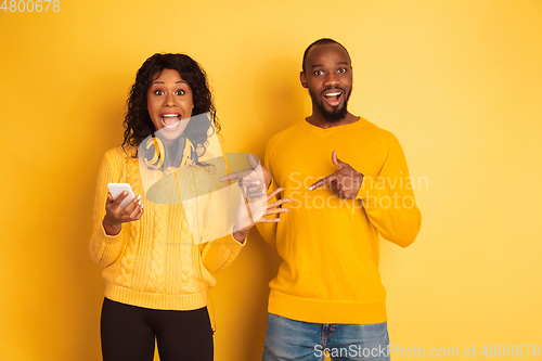 Image of Young emotional african-american man and woman on yellow background