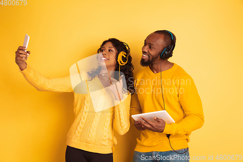 Image of Young emotional african-american man and woman on yellow background