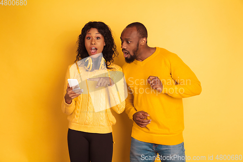 Image of Young emotional african-american man and woman on yellow background