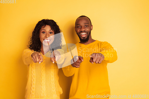 Image of Young emotional african-american man and woman on yellow background