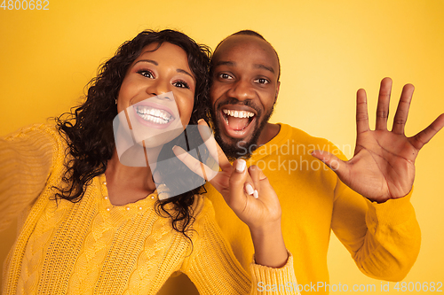 Image of Young emotional african-american man and woman on yellow background