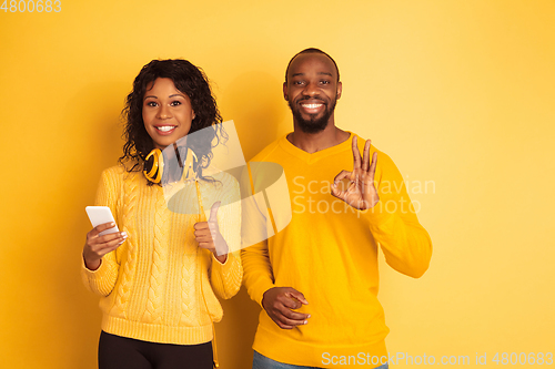 Image of Young emotional african-american man and woman on yellow background