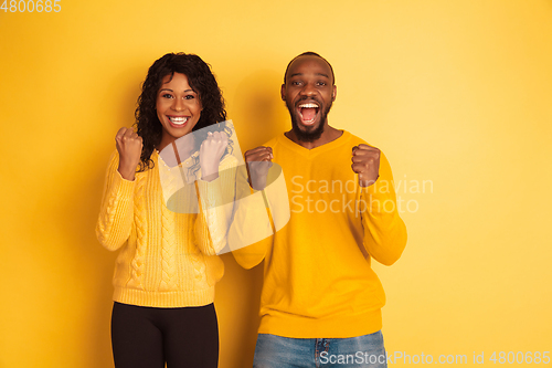 Image of Young emotional african-american man and woman on yellow background