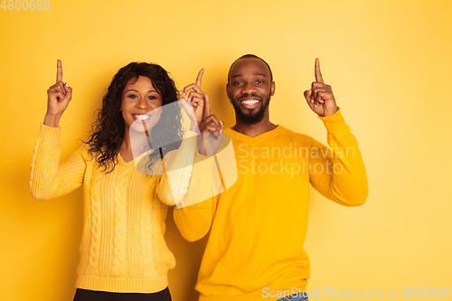 Image of Young emotional african-american man and woman on yellow background