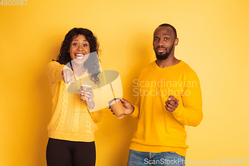 Image of Young emotional african-american man and woman on yellow background