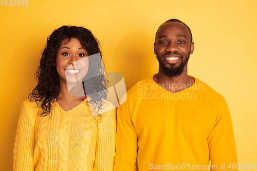 Image of Young emotional african-american man and woman on yellow background