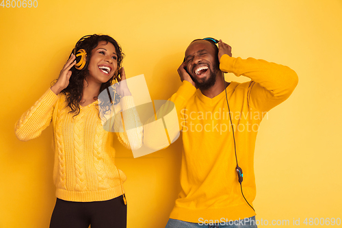 Image of Young emotional african-american man and woman on yellow background